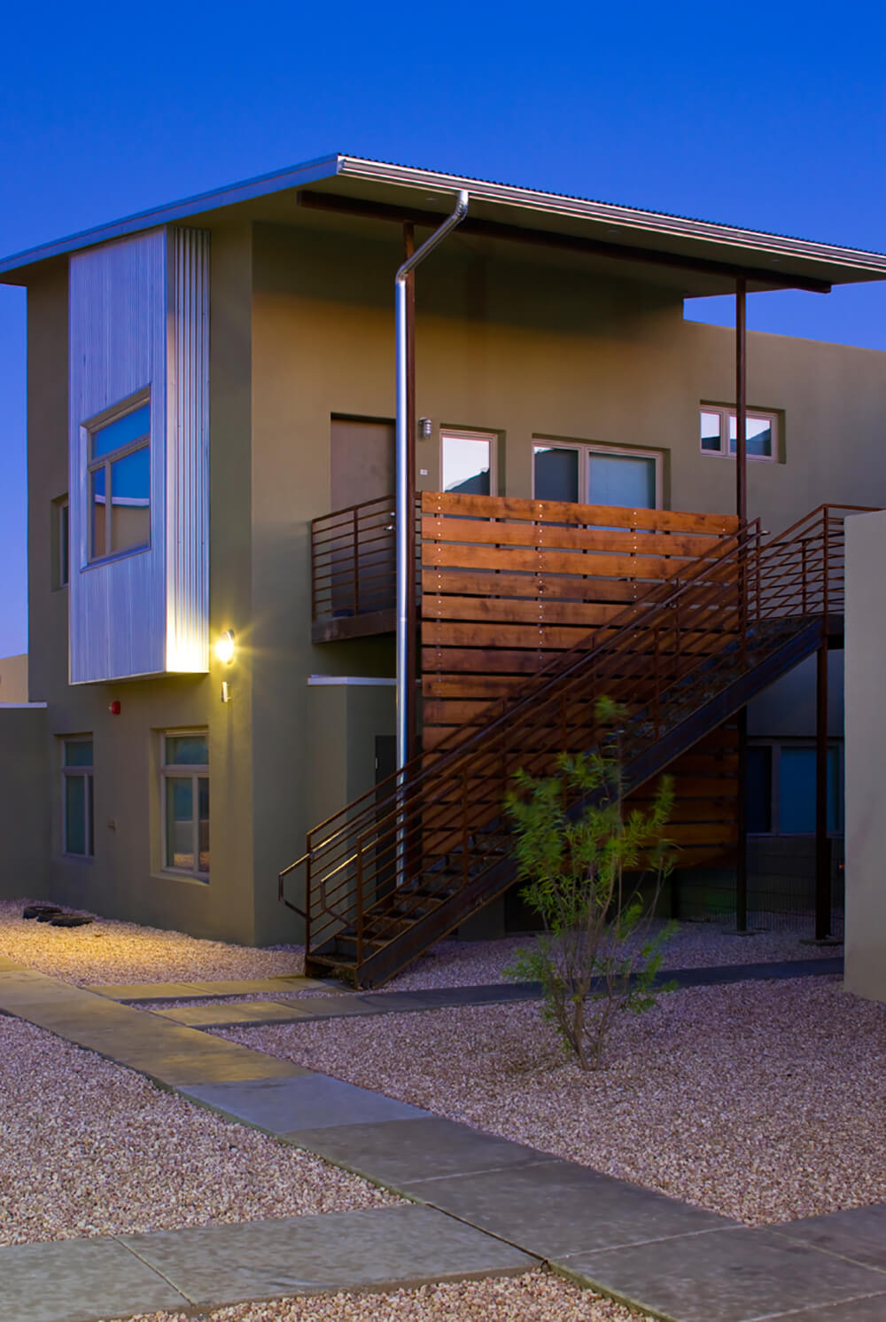 Steel stairway and wood balcony screen of a two-story home at dusk at La Pradera in Hobbs, New Mexico